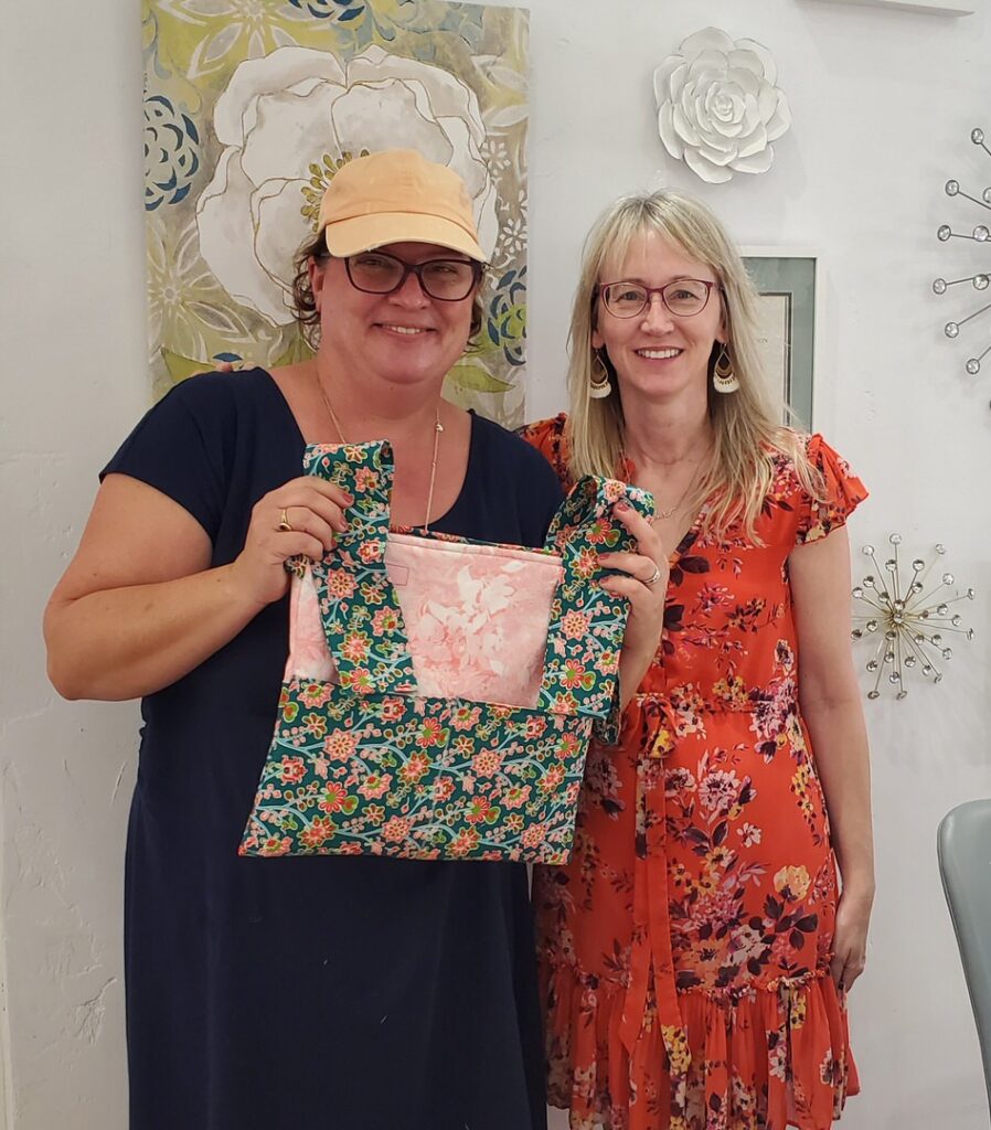 Visitor volunteer Jessica with The Sewing Hui founder Jennifer Oberg, showcasing walker bags